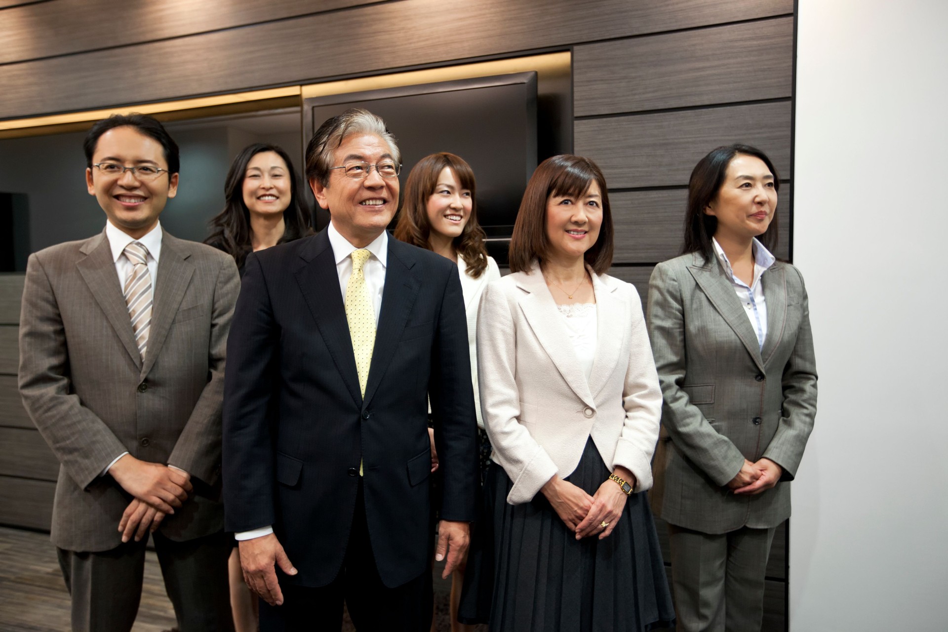 Happy mature Japanese businessman with his team in corporate interior